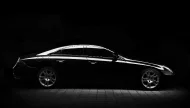 An elegant black and white studio-style profile shot of a Mercedes-Benz CLS-Class luxury coupe, with dramatic lighting sculpting its sleek body lines against a solid black background.